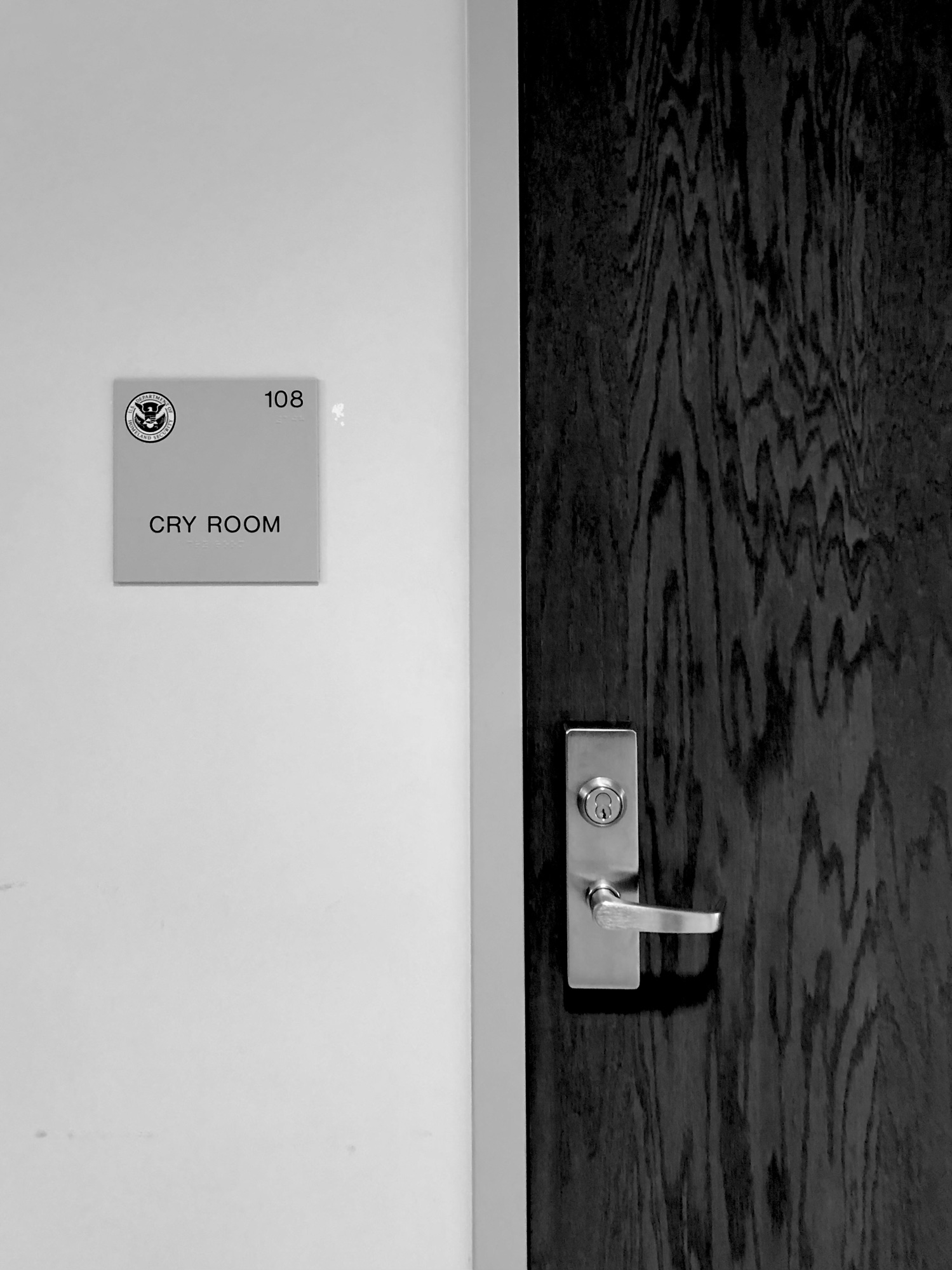 A stark photo of a sterile scene. A door to a room marked by a sign designating a Cry Room.