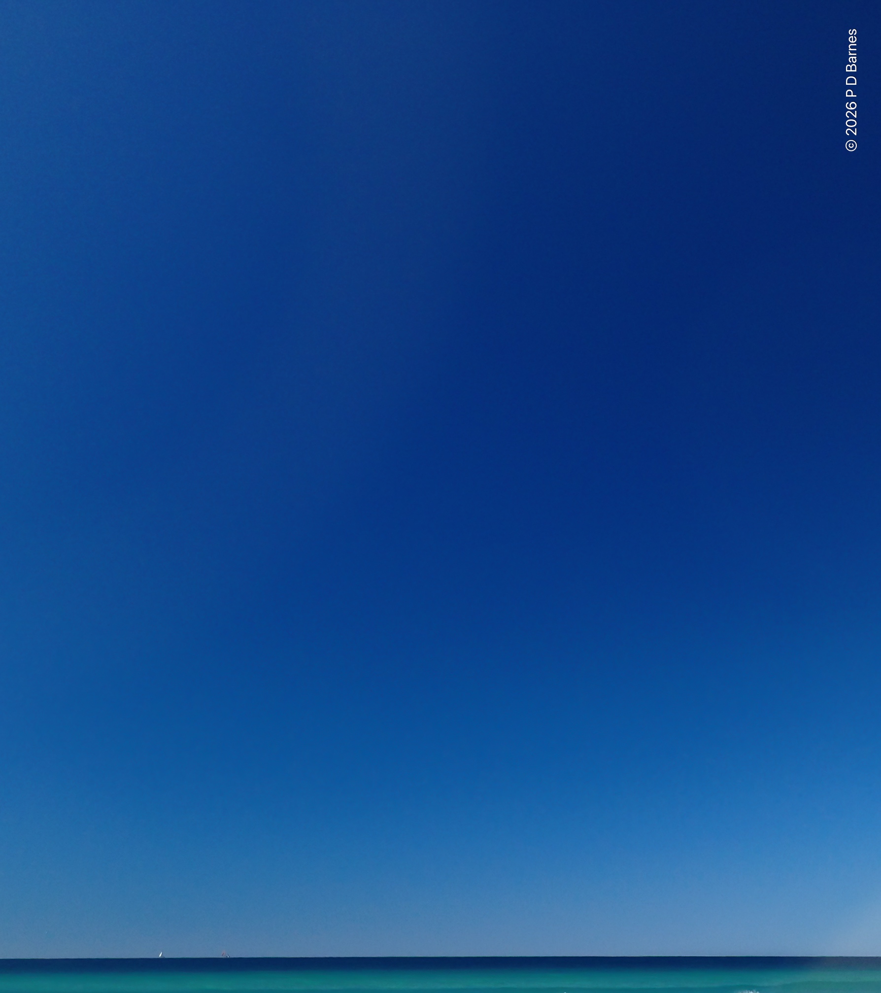 A deep blue sky over a deep blue sea, shifting suddenly to turquoise as the bottom shelves up steeply towards the unseen beach.